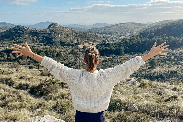 Melli Ketter breitet die Arme vor einer Landschaft aus. Transformation im Körper. 